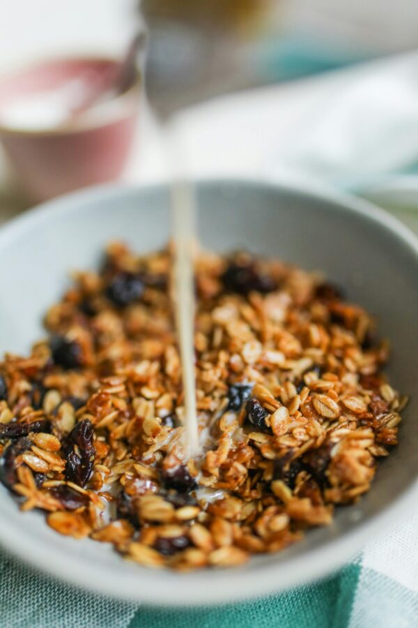 A close-up of granola in a bowl with milk being poured over it, highlighting health and nutrition.